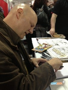 SAVAGE DRAGON creator Erik Larsen sketches for a fan at his table in Artists' Alley