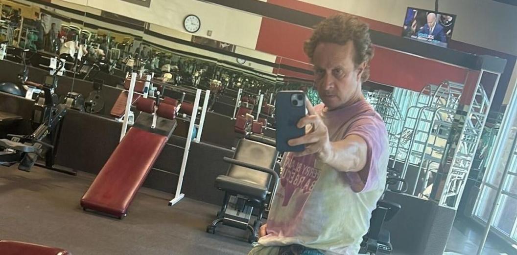 Pauly Shore taking a gym selfie in a tie-dyed shirt