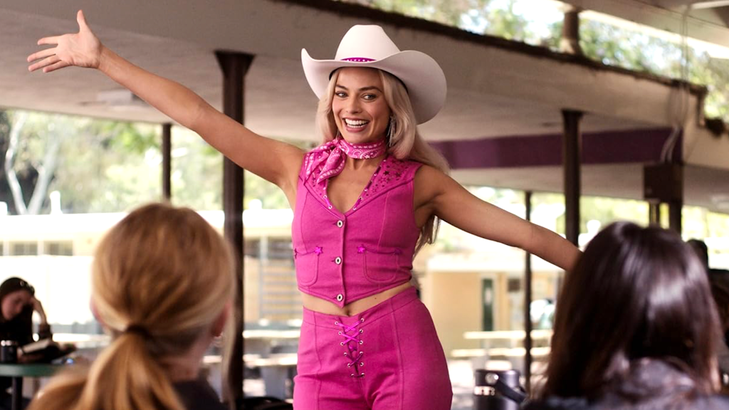 Margot Robbie as Barbie in Barbie wearing pink outfit and white hat.