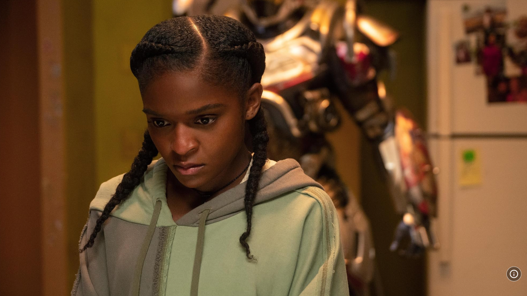 Dominique Thorne wearing green hoodie with Ironheart mechanical suit behind her.