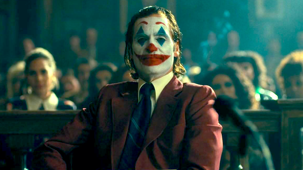 Joaquin Phoenix as Arthur Fleck wearing red suit and Joker makeup in Joker: Folie à Deux