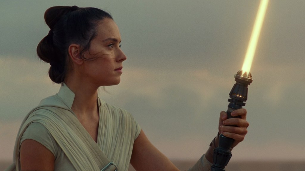 Rey Skywalker holding up her lightsaber