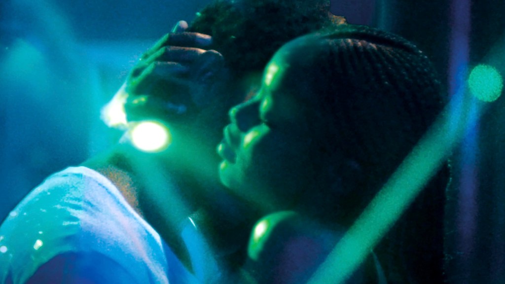 Two people embracing with blue and green lighting