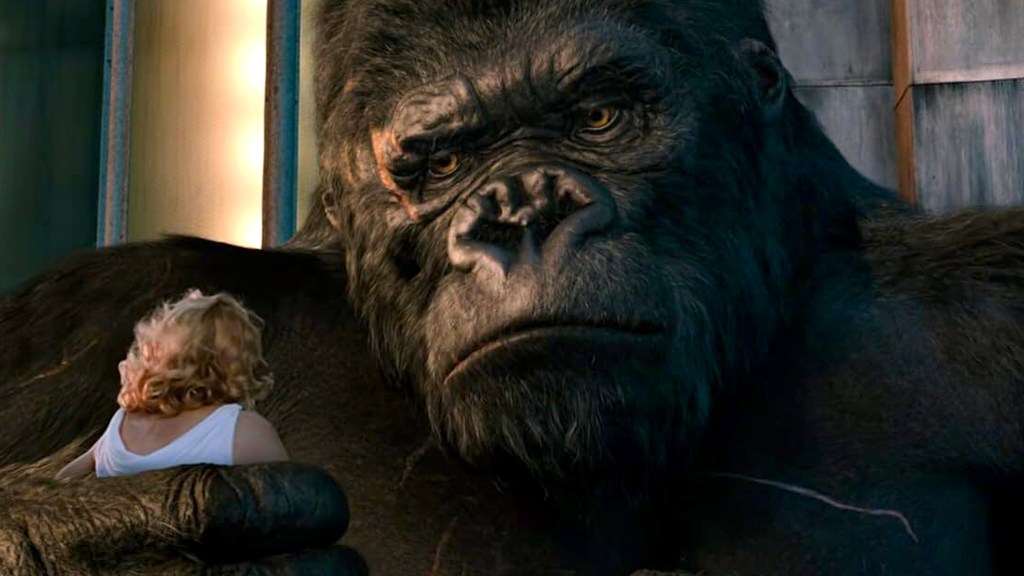 Close -up of King Kong sosteniendo a una mujer con cabello rubio.