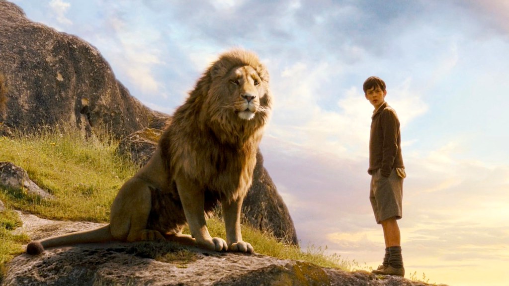 Lion and Skandar Keynes' Edmund standing on a grassy cliffside in The Chronicles of Narnia: The Lion, the Witch, and the Wardrobe