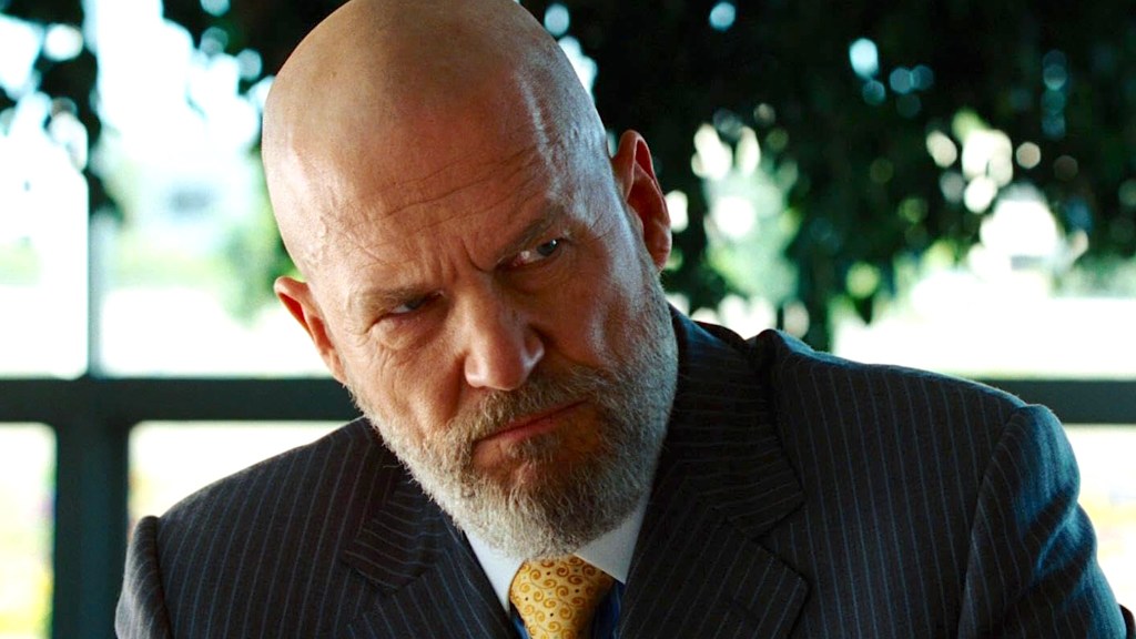 Jeff Bridges as Obadiah Stane staring menacingly, wearing black suit