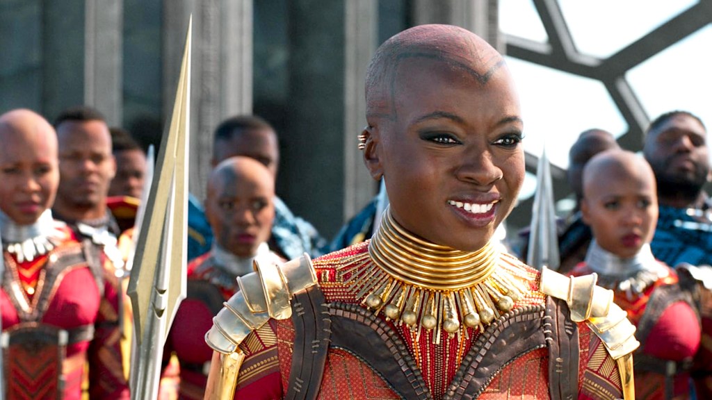 Danai Gurira as Okoye smiling with Dora Milaje behind her in Black Panther