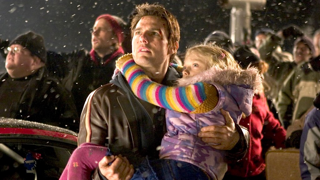 Tom Cruise holding child with people in the background and snowflakes in the air in War of the Worlds