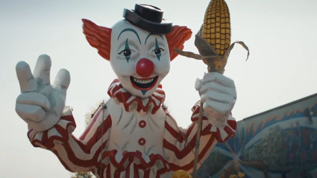 Shudder's Clown in a Cornfield Trailer Promises Movie to Be a Thing of Nightmares
Shudder has unveiled the official green band trailer for their upcoming slasher film Clown in a Cornfield, showcasing a blood-soaked rampage through the fictional town of Kettle Springs at the hands of a murderous mascot named Frendo. The horrifying two-minute preview reveals the killer clown employing an impressive arsenal of weapons against his teenage victims, including crossbows, sickles, chainsaws, and repurposed sports equipment in increasingly creative and brutal murder sequences. Based on Adam Cesare's popular young adult horror novel, the film appears to lean heavily into both the rural setting and the killer clown iconography that has proven successful for the horror genre in recent years. The trailer shows director Eli Craig has crafted a visually striking slasher film that balances traditional horror elements with innovative kill scenes, positioning the adaptation as a must-watch for genre enthusiasts when it arrives in theaters on May 9, 2025, following its well-received premiere at South by Southwest earlier this month.
Clown in a Cornfield green band trailer introduces viewers to the horror film's premise through protagonist Quinn (Katie Douglas), who moves with her father (Aaron Abrams) to the struggling town of Kettle Springs, a community divided following the closure of the Baypen Corn Syrup Factory. Soon after Quinn’s moving, the factory's mascot, Frendo, emerges from the surrounding cornfields to begin a murderous purge. The creative team appears to have embraced the inherent creepiness of clowns, with Frendo's permanently fixed grin and pork-pie hat creating an unsettling silhouette against the rural landscape.
https://youtu.be/8tBSOKyyZT8?si=O5ag9t6G_TO0FHw_
[RELATED: 7 Movies to Watch After Terrifier 3]
The adaptation of Clown in a Cornfield marks a significant milestone for author Adam Cesare, whose novel has spawned a successful trilogy with the most recent entry, The Church of Frendo, published last year. While the film industry has long mined literary horror for adaptations, young adult novels have rarely received the R-rated treatment suggested by this trailer's graphic content. The screenplay, co-written by Craig and Carter Blanchard, appears to preserve the novel's generational conflict themes while amplifying the visceral horror elements.
From Cornfield to Screen: How Eli Craig Brought Frendo to Life
The journey to bring Clown in a Cornfield to theaters began in 2020 when Temple Hill Entertainment, fresh off producing the successful horror film Smile, acquired the rights to Cesare's novel before it had even hit bookshelves. The production company, known for both the Twilight and Maze Runner franchises, recognized the potential of combining the resurgent killer clown subgenre with contemporary themes of small-town American decline. Director Eli Craig, who established himself in the horror-comedy space with the cult favorite Tucker & Dale vs. Evil, signed on to helm the adaptation alongside screenwriter Carter Blanchard, whose previous credits include Independence Day: Resurgence.
Early reception from the film's South by Southwest premiere has been overwhelmingly positive, with several critics highlighting it as one of the year's standout horror releases thus far. The film's May theatrical release through RLJE Films and Shudder positions it as a counter-programming alternative to early summer blockbusters, similar to the strategy that helped Smile become a surprise hit in 2022.
Are you watching Clown in a Cornfield in theaters? Are you excited about the movie? Let us know in the comments!

