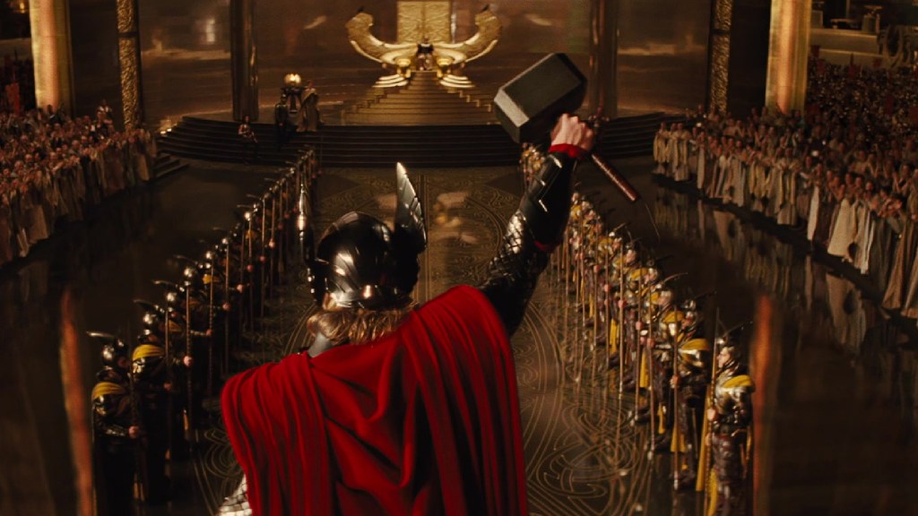 Thor raising Mjolnir in front of a crowd on Asgard in Thor (2011)