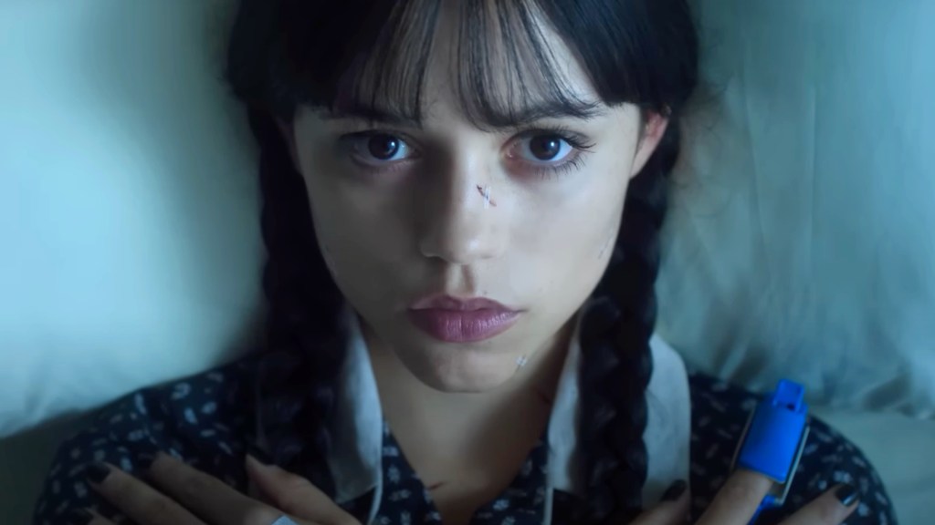 Jenna Ortega as Wednesday Addams lying in a hospital bed