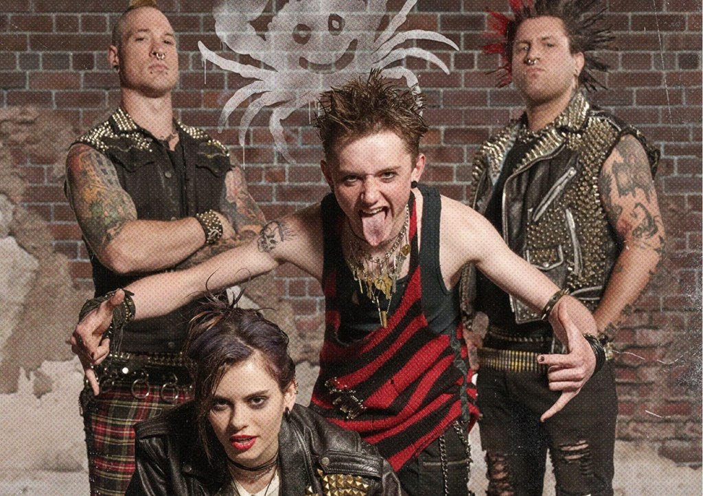 The members of the band the Mighty Crabjoys standing together in front of a brick wall with their logo behind them
