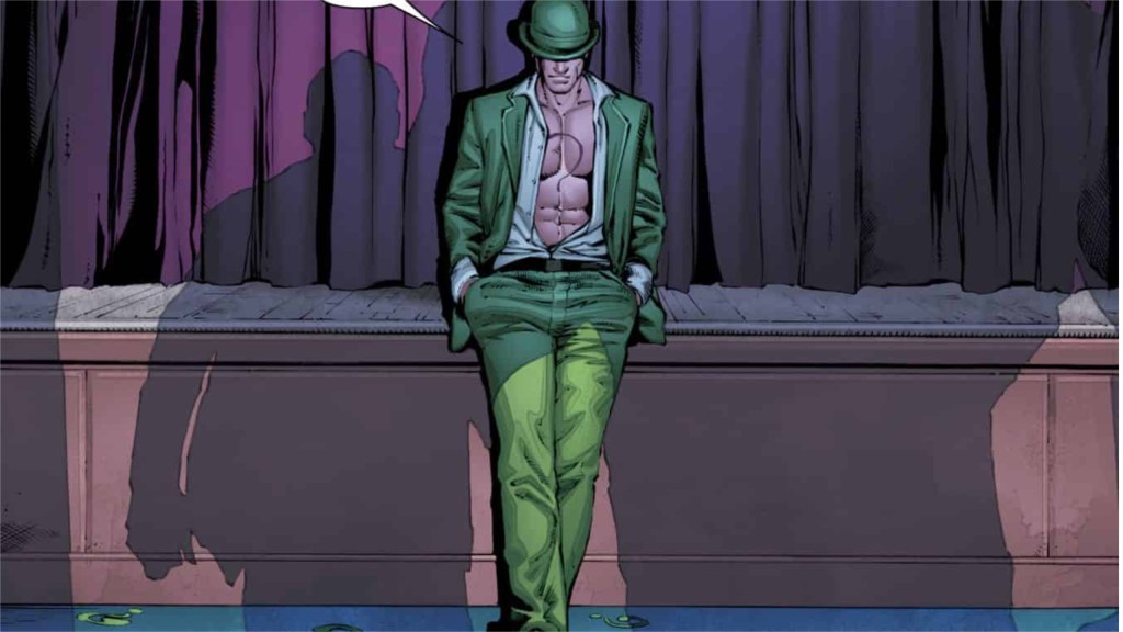 Riddler leaning against the edge of a stage with purple curtains