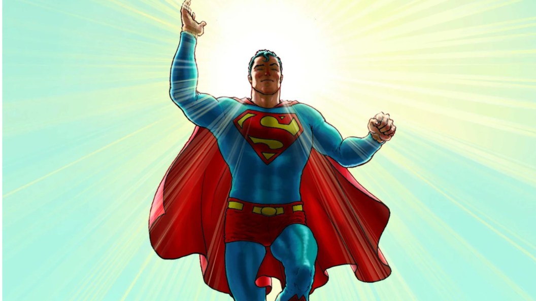 Superman in the sun waving, his cape flapping in the wind