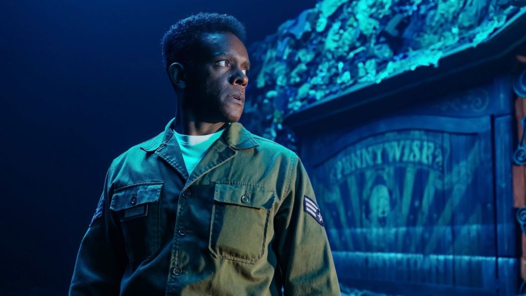 Chris Chalk as Dick Hallorann near a Pennywise sign board in IT Welcome to Derry