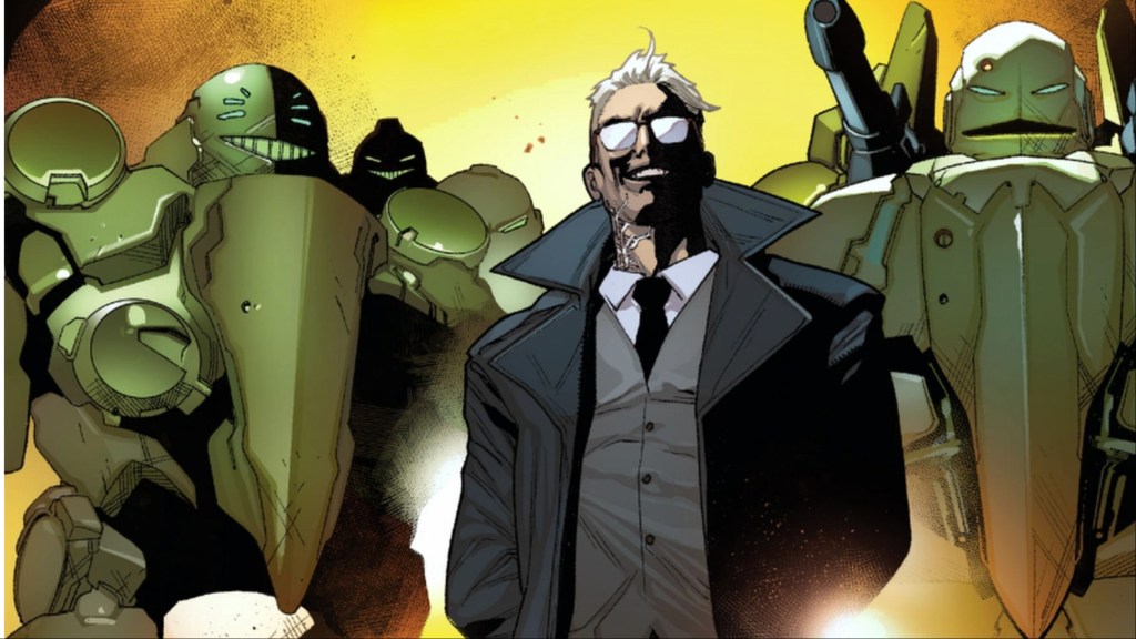 Cameron Hodge smiling evilly in front of two massive robots