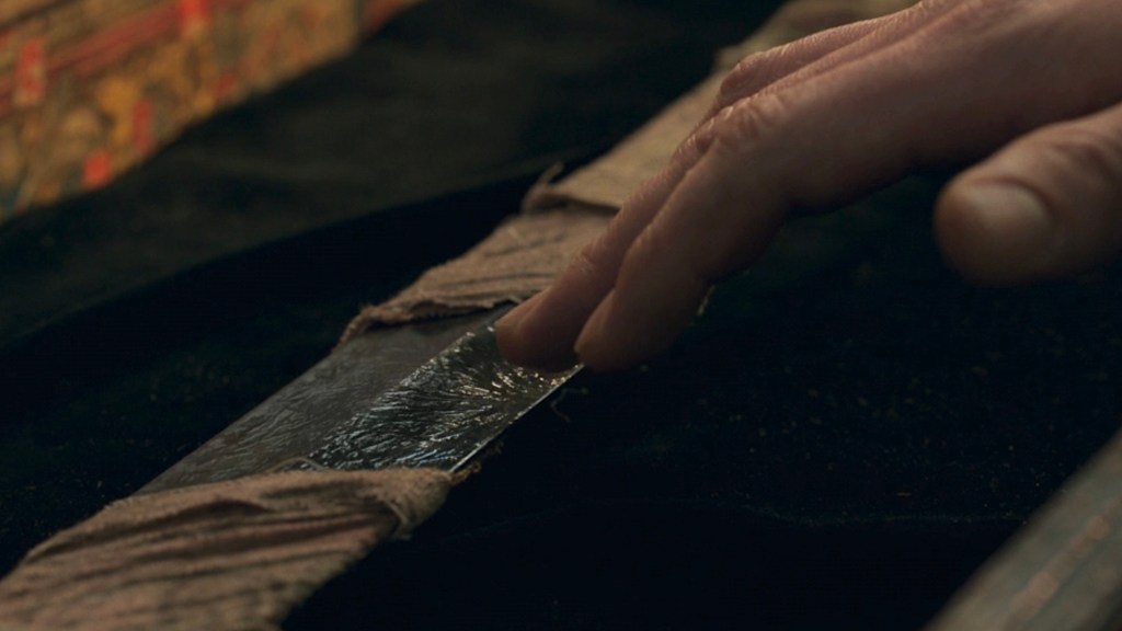 Hand touching the Ebony Blade in Eternals
