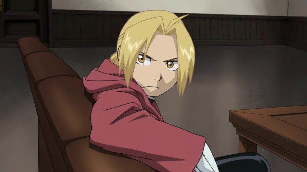 Edward Elric sitting in a chair and looking annoyed in Fullmetal Alchemist: Brotherhood