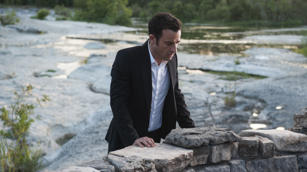Justin Theroux as Kevin Garvey leaning on a brick wall in front of water in The Leftovers