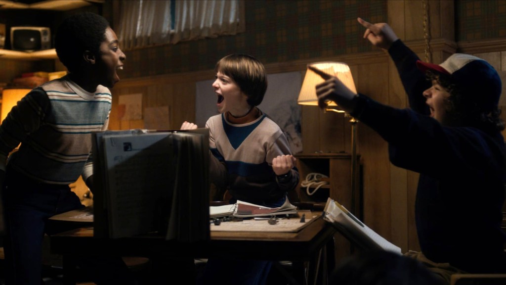 Lucas, Will, and Dustin celebrating while playing Dungeons & Dragons in Stranger Things