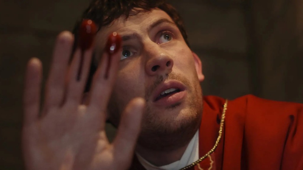 Josh O'Connor as Father Jud holding up a bloody hand in Wake Up Dead Man