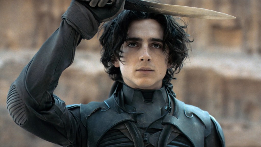 Timothee Chalamet as Paul Atreides holding up a blade in Dune
