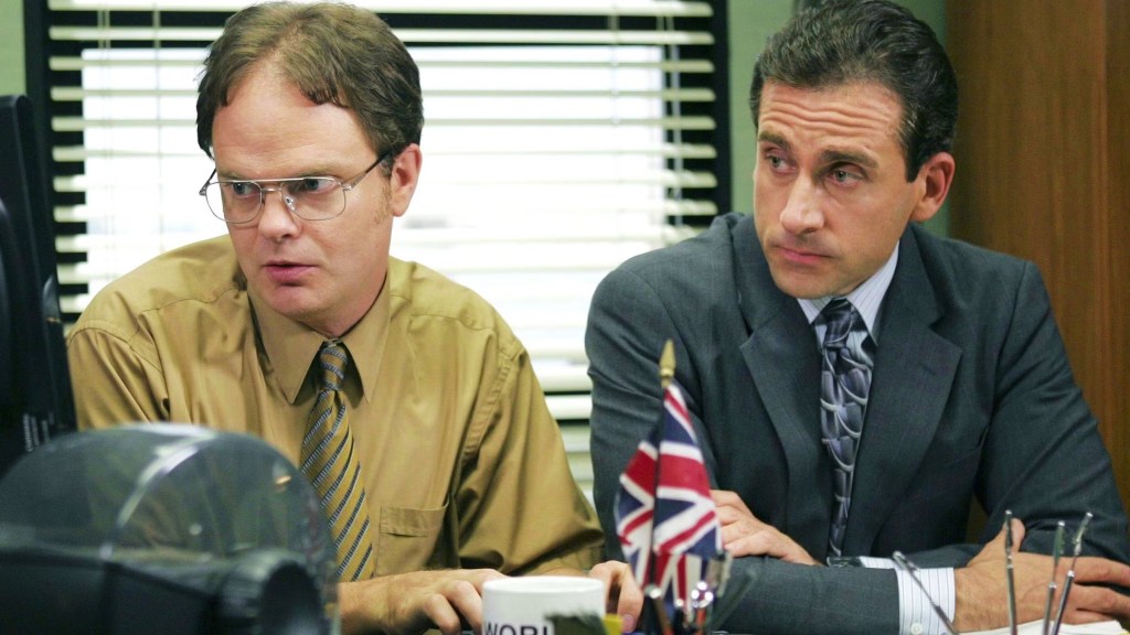 Dwight and Michael Scott in The Office sitting together at Michael's desk.