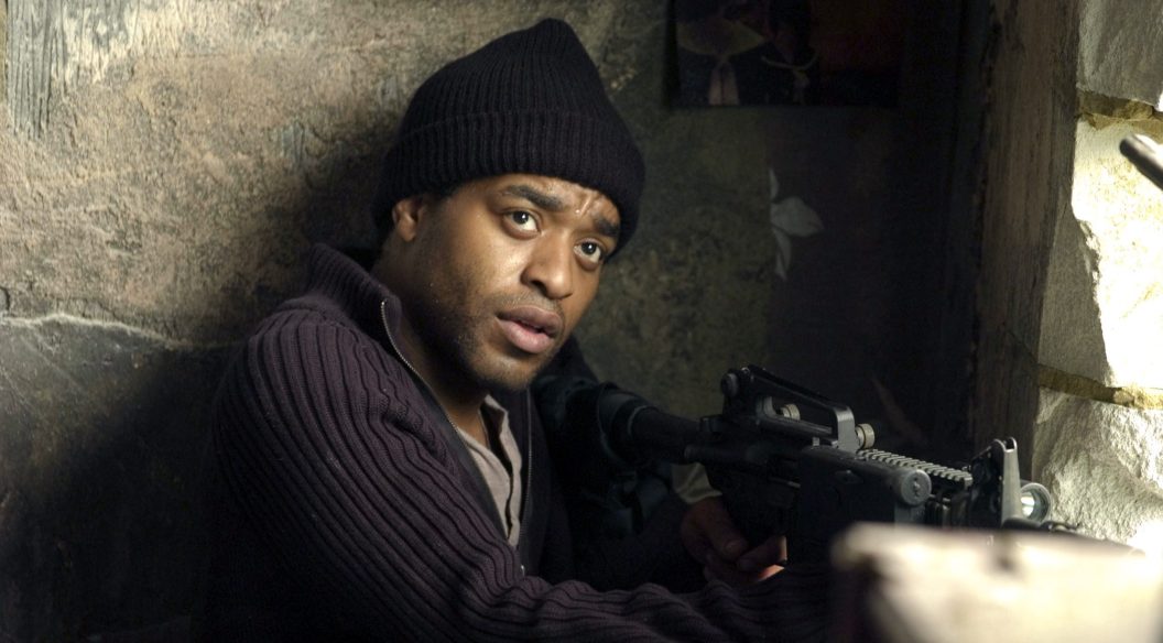 A man wearing a black beanie had holding a gun, resting against a wall.