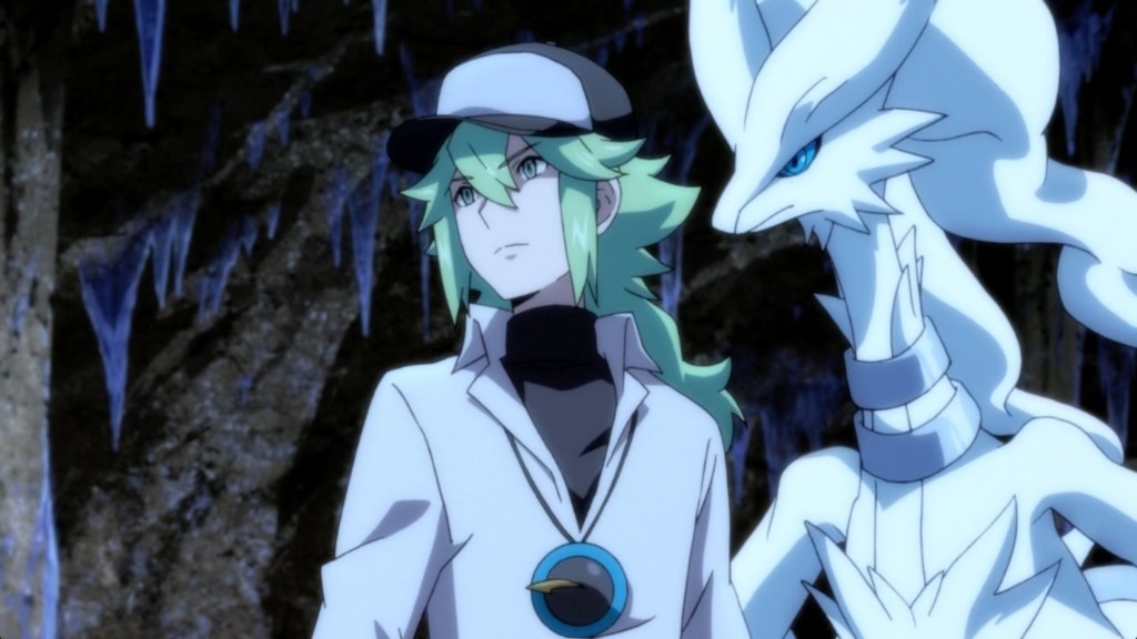 N from Pokemon Generations, posed in a dark cave with green hair and a baseball cap. Beside him is his Pokemon partner, Reshiram.